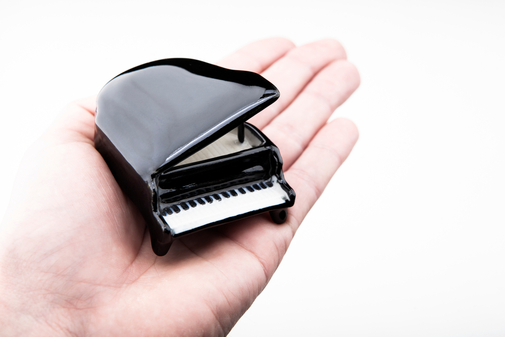 miniature grand piano on palm 